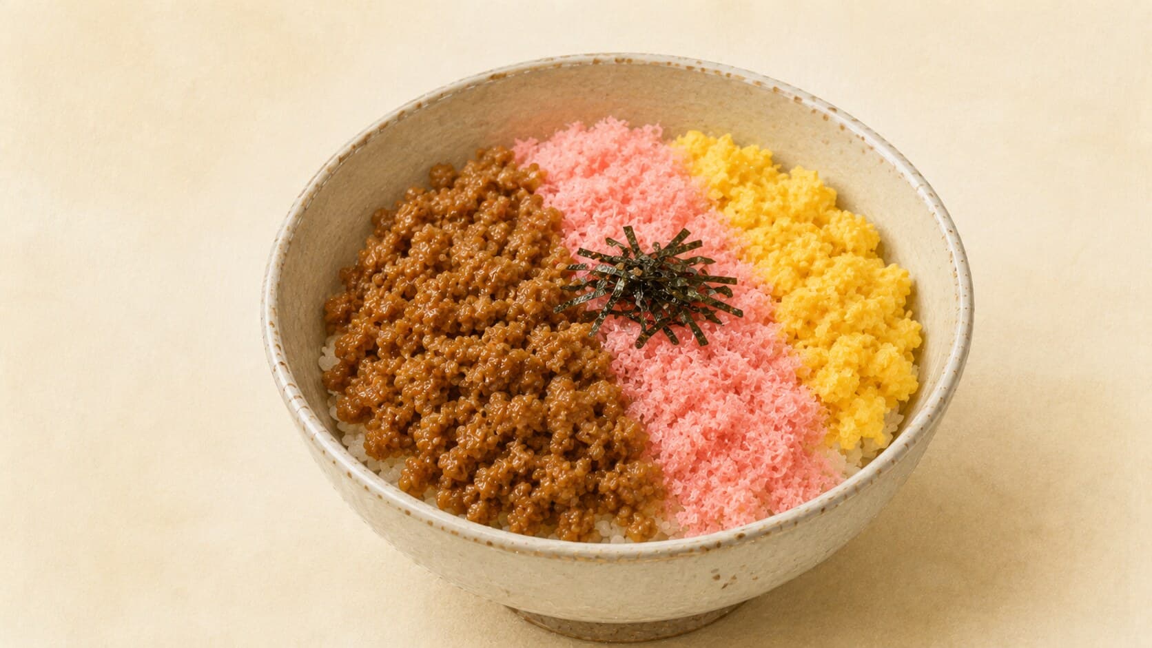 A simple Japanese soboro rice bowl in a rustic ceramic bowl — white rice topped with three clean sections: glossy brown chicken soboro on the left, soft yellow scrambled egg soboro on the right, and delicate pink sakura denbu in the center, with a small garnish of shredded nori